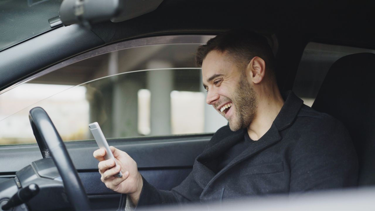 services-03 Young man enjoying a moment with his smartphone inside a car.