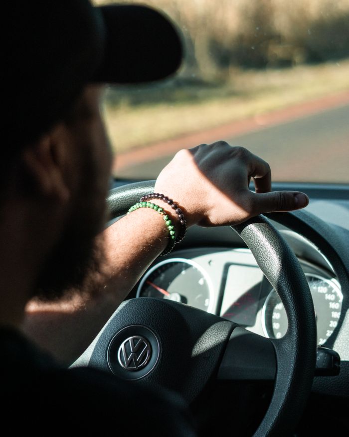 gallery-5 A man driving a Volkswagen car on a sunny day focusing on the road ahead.