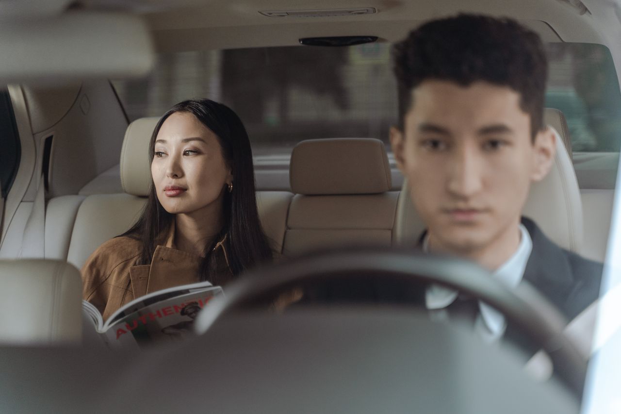 hero-img-02 Asian businesswoman and male chauffeur in a luxury car interior, representing travel comfort and professional transportation.